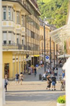 Lively street scene in a sunny town with pedestrians and bicycles, Merano, Italy