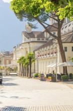 Picturesque street lined with palm trees and inviting café, classic buildings in the background,