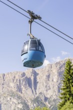 Blue cable car gondola floating in front of an impressive mountain range under a clear sky, Alpe di