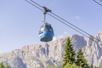 A cable car gondola crosses rocky landscapes against a clear blue sky, Alpe di Siusi, Dolomites,