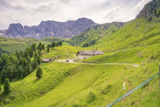 A village with buildings in the middle of a green, hilly mountain landscape, Alpe di Siusi,