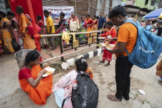 Devotees eating food near a street as they arrives to visit Kamakhya Temple during Ambubachi Mela,