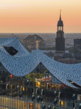 Aerial view of the Elbphilharmonie at sunset with illuminated windows and view over Hamburg and the