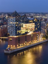 Aerial view of the Elbphilharmonie at blue hour with illuminated windows and view over the