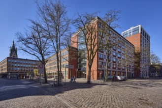 Stadthaus 1, city centre, brick building, bare wintry trees, cobblestone street, blue cloudless