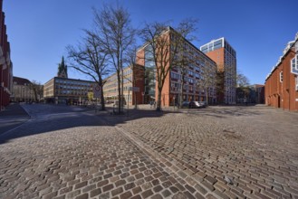Stadthaus 1, city centre, brick building, bare wintry trees, cobblestone alleyway, blue cloudless