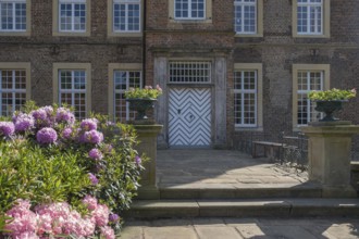 An elegant entrance to a historic brick building with flowering plants, Haus Welbergen, Ochtrup,