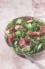 Fresh arugula salad with prosciutto and grated parmesan cheese, on a plate, homemade, no people