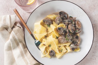 Delicious pappardelle pasta with mushrooms and cream served on a white plate
