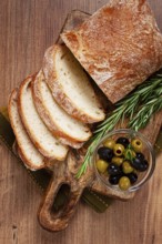 Sliced ciabatta, on a chopping board, with rosemary and olives, Italian bread, close-up, Italian