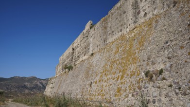 Defence wall, Fortress wall, Large stone wall with moss and vegetation under a clear sky,
