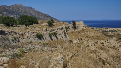 Rocky ruins on a coastal landscape with sea and sunny sky, Kardamina, Antimacheia, Medieval