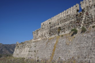 Defence wall, Outer wall, Extensive stone fortifications with vegetation under blue sky,