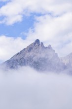 An isolated mountain peak rises through fog into the clear sky, Dolomites, South Tyrol, Dolomites,