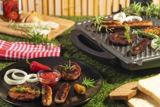 Burgers and sausages on a plate and grill with bread, rosemary and ketchup in a summery atmosphere