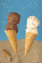Two ice cream cones, one with chocolate ice cream and one with cream ice cream, against a blue