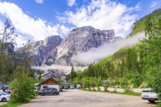 Car park in front of an impressive mountain landscape with cars and buildings in the countryside,
