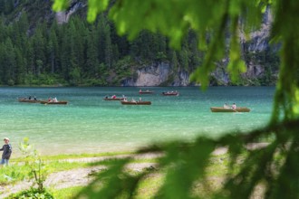 Several boats on a turquoise-coloured lake, surrounded by a green forest and summer atmosphere,