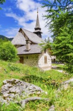Stone church with characteristic tower in a green, sunlit landscape, Lake Braies, South Tyrol,