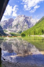 Clear lake with mountain reflection and boats, surrounded by dense forest, Pragser Wildsee, South