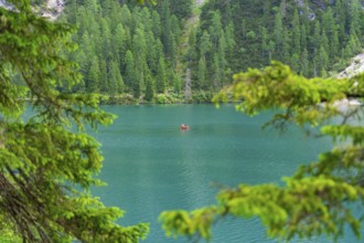 A single boat on a calm turquoise-blue lake, framed by green trees, Pragser Wildsee, South Tyrol,