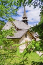 An idyllically situated church with a pointed tower, surrounded by dense vegetation, Lake Braies,