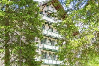 A hotel building with green trees and balconies in a wooded setting, Lake Braies, South Tyrol,
