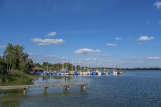 Peaceful scenery with sailing boats at the jetty and blue sky, Chiemsee, Bavaria, Germany