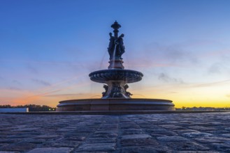 The three graces fountain in bordeaux, france, stands majestically against a vibrant sunrise sky,