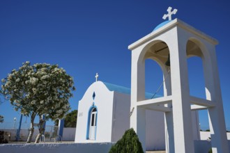 Chapel of Agios Charalambos, White chapel with bell tower and blossoming tree in the background,