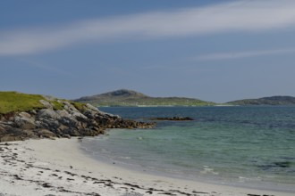 Quiet beach with white sand and rocks, surrounded by blue sea and clear sky, Eriksay, South Uist,