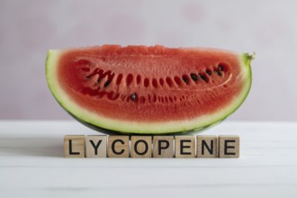 Watermelon slice with wooden blocks spelling Lycopene. Studio image emphasizing summer freshness