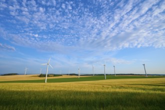 A row of wind turbines on green fields under a cloudy sky, summer, Höhefeld, Wertheim,