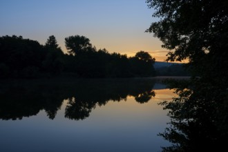 Morning sky over a quiet river Main with trees silhouetted against the orange light, summer,