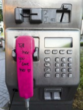 Telephone receiver of a Telekom payphone with the inscription Tell her you love her in Wuppertal,