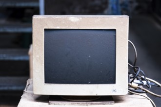 An old, dusty CRT monitor (cathode ray tube monitor) with a beige-grey housing. Significant signs