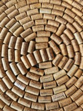 A large number of wine corks laid close together in a spiral pattern. The corks come from different