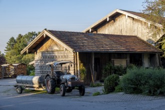 Rural scene with a wooden house and a tractor in the evening light, surrounded by nature, Bavaria,