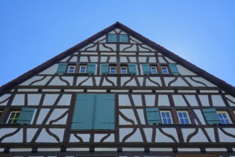 Gable facade of a half-timbered house with green shutters against a blue sky, Triberg im