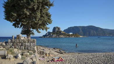 Summer beach view with view of a small island and chapel, Agios Stefanos Beach, Agios Stefanos