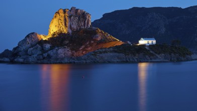 An idyllic night view of an illuminated island with a chapel and calm sea, Agios Stefanos Beach,