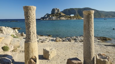 Ancient columns on the coast with a view of an island and the blue sea, Agios Stefanos Beach, Agios