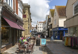 People sitting in street outside Reeve cafe bakery, Butcher Row, Salisbury, Wiltshire, England, UK
