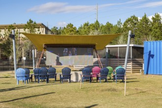 Big screen television under an awning at The Fort outdoor dining and entertainment hangout composed