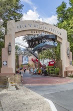 Masked park guests exiting under the entrance sign for the Rock 'n' Roller Coaster ride at Disney's