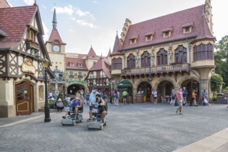 Masked park guests walking and riding scooters through the Germany pavilion of Epcot at Walt Disney