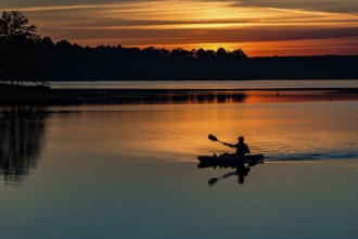 Man paddling his kayak at sunset on the lake at Little Black Creek campground near Lumberton,