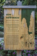 Wooden sign in Thai and English describes the Mae Fah Luang Garden inside the Doi Tung tourist