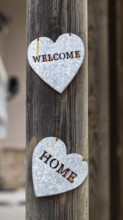 Welcome Home message in galvanized metal hearts on a wood post
