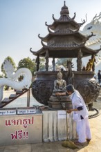 Worker cleaning Buddhist statue in fron of the Guan Yin (Goddess of Mercy) statue at Wat Huay Pla